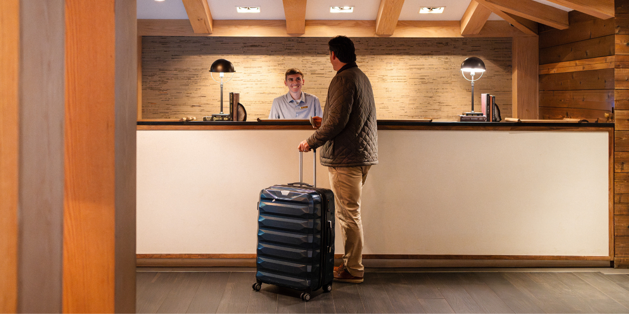 A man stands with luggage in front of the check-in desk at Gurney's Montauk Resort