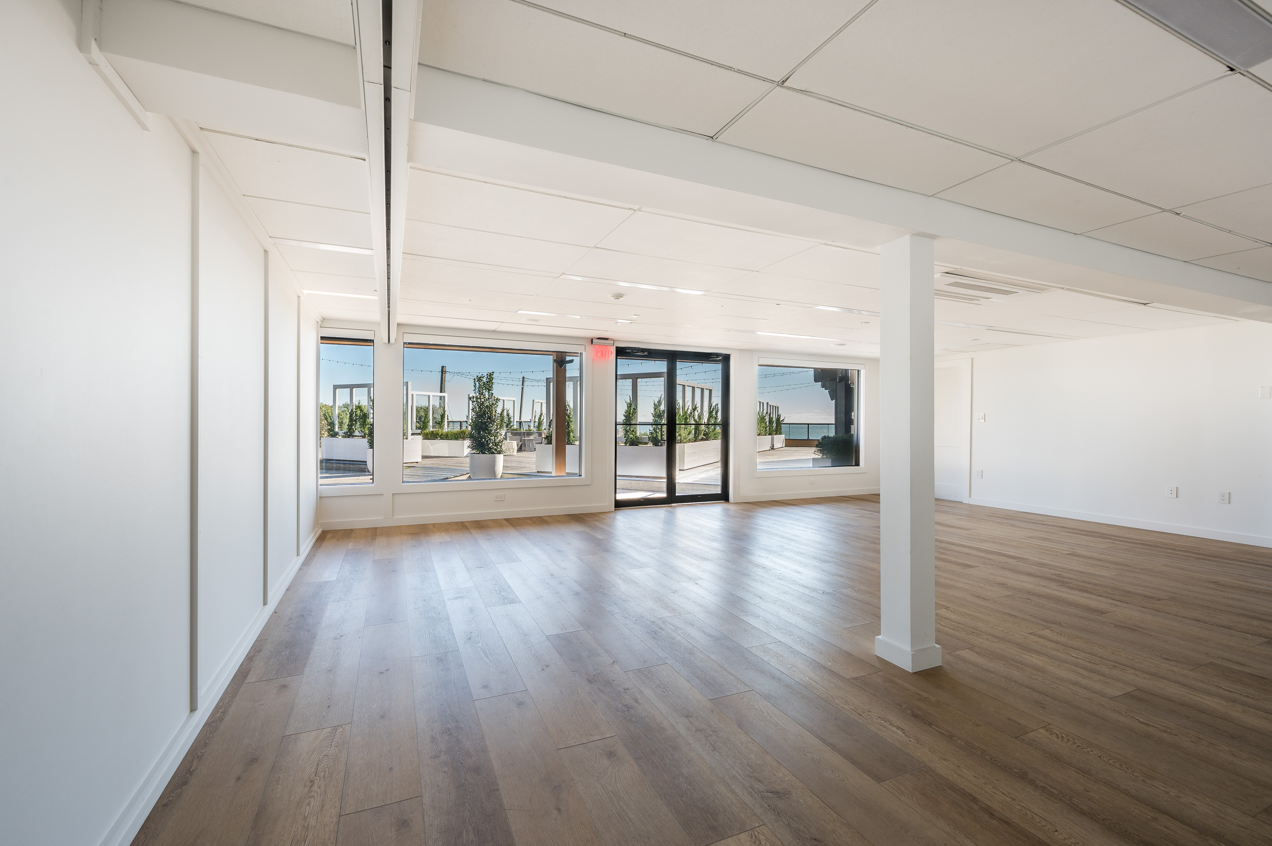 Latitude meeting venue with dark wood flooring, white walls and pillar, large windows with ocean view.