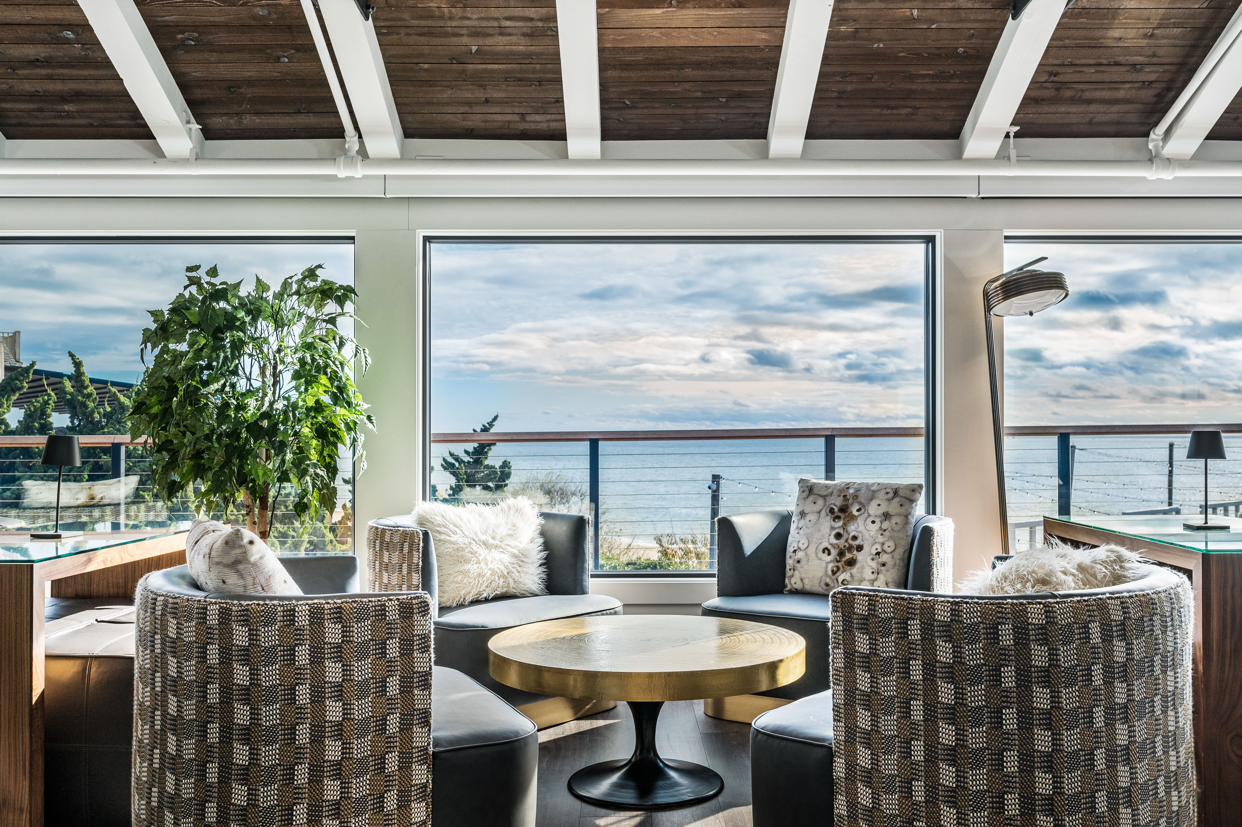 The Regent Lounge detail shot with four chairs with detailed upholstery and pillows surrounding gold round-top table overlooking ocean views.