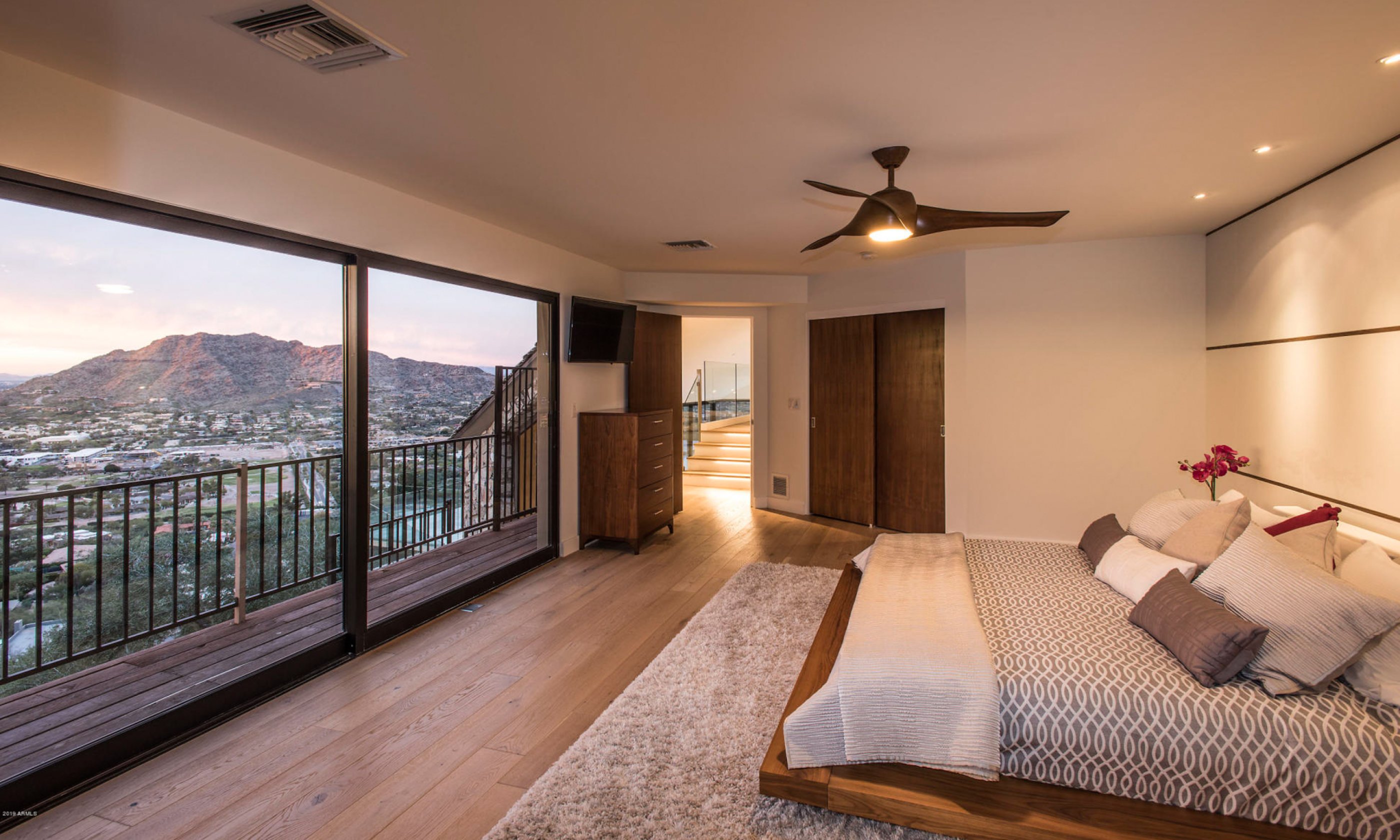 Bedroom with king bed, ceiling fan and floor-to-ceiling window showing surrounding valley.