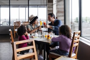 A family of four sits at a table enjoying a meal in the Scarpetta Beach dining room