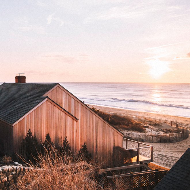 Sunset over a wooden building with beach and ocean in background