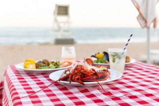 Lobster bake meal on a red checked table cloth on the beach