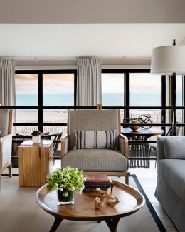Sitting area with sofa, armchairs, and coffee table, with a view out onto the beach