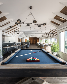 A pool table set with billiard balls in the foreground, with the Regent Lounge at Gurney's Montauk in the background.