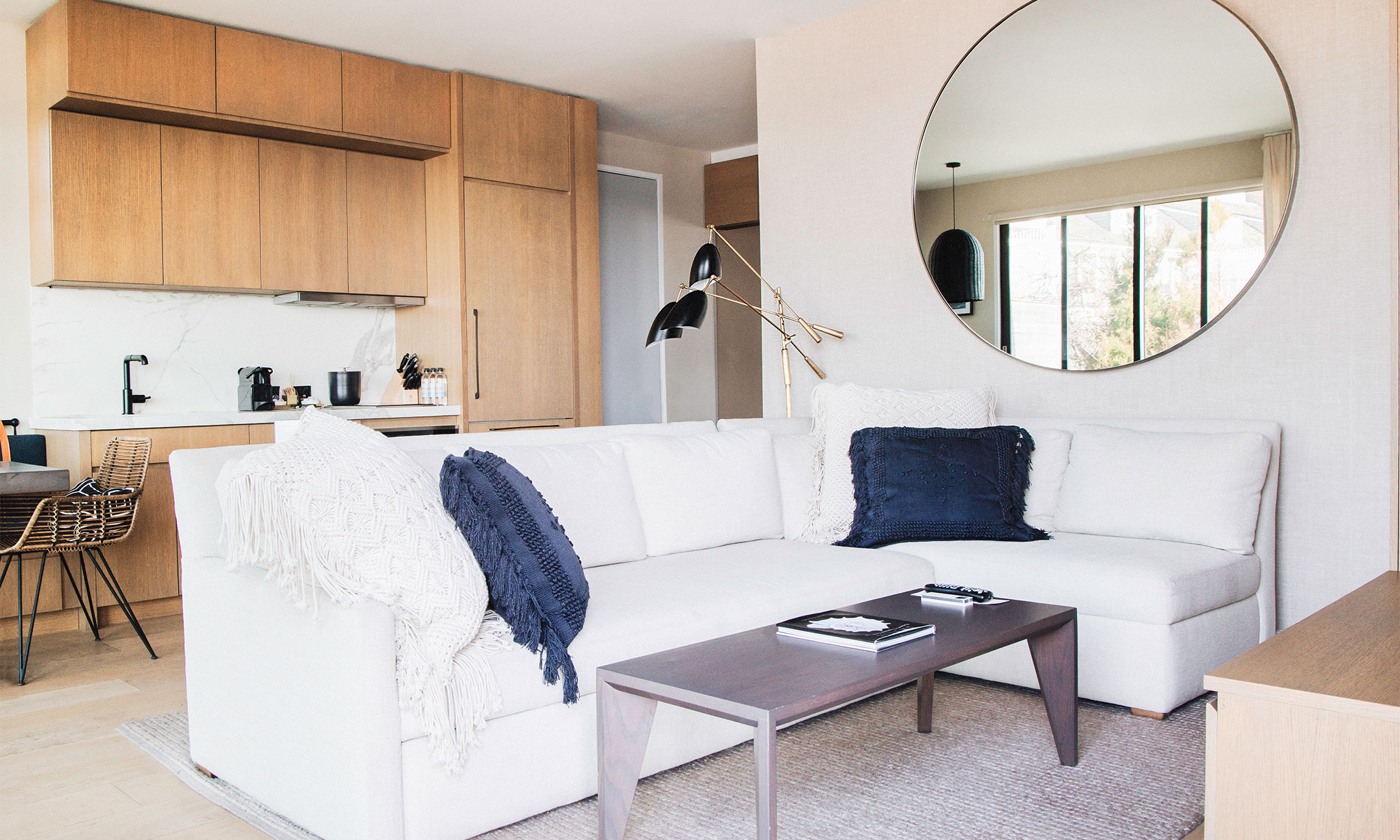 Sectional sofa in living area with coffee table and large circle mirror