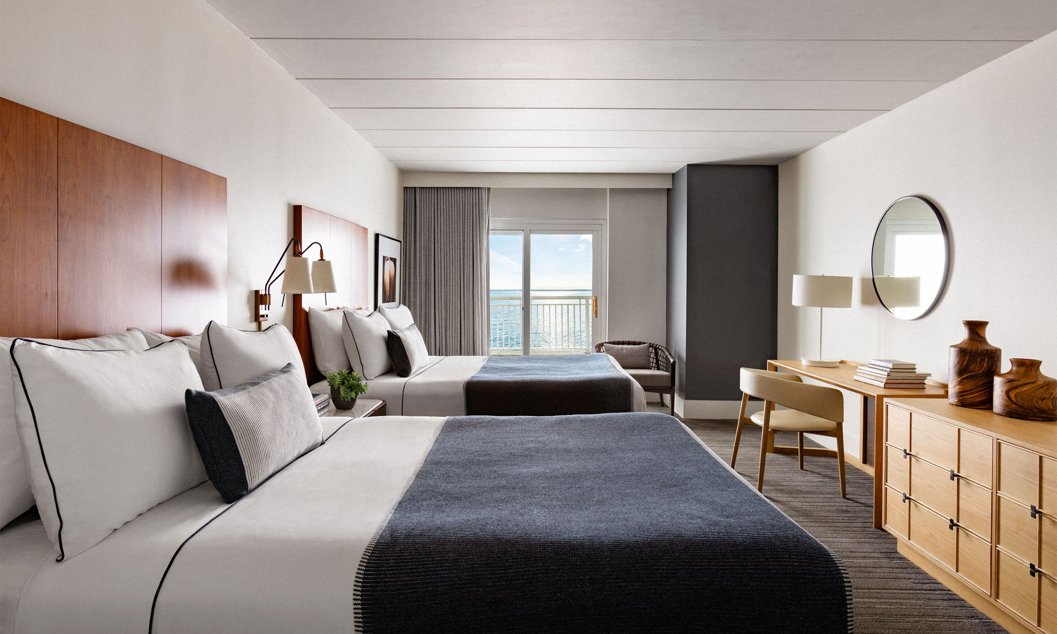 two queen beds with work area overlooking balcony with water view