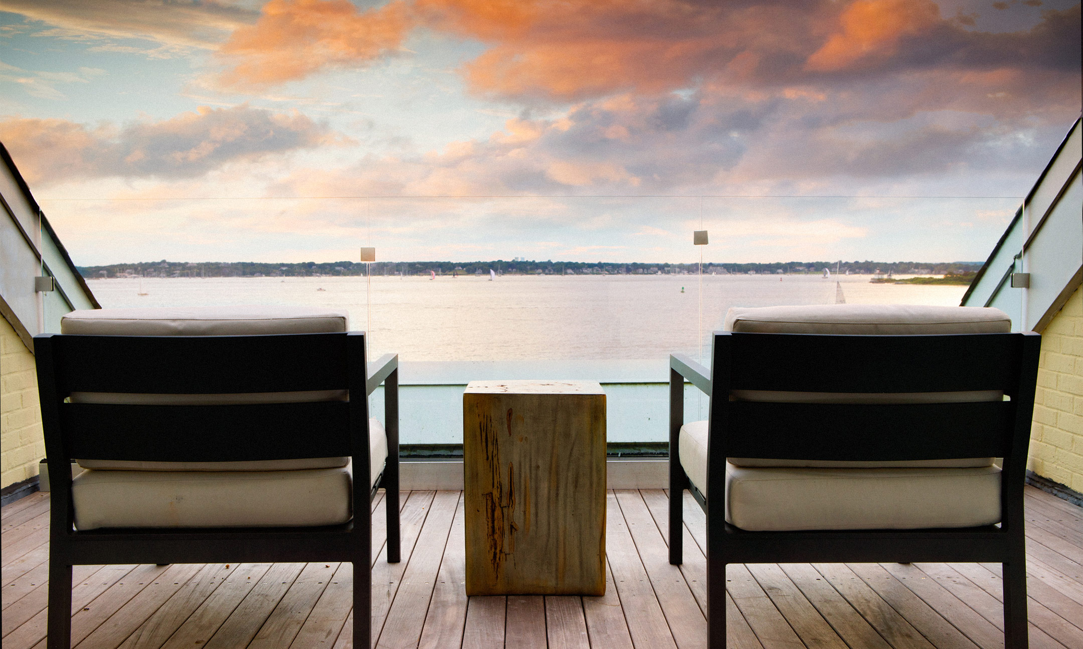 two chairs on balcony looking at sunset over the water