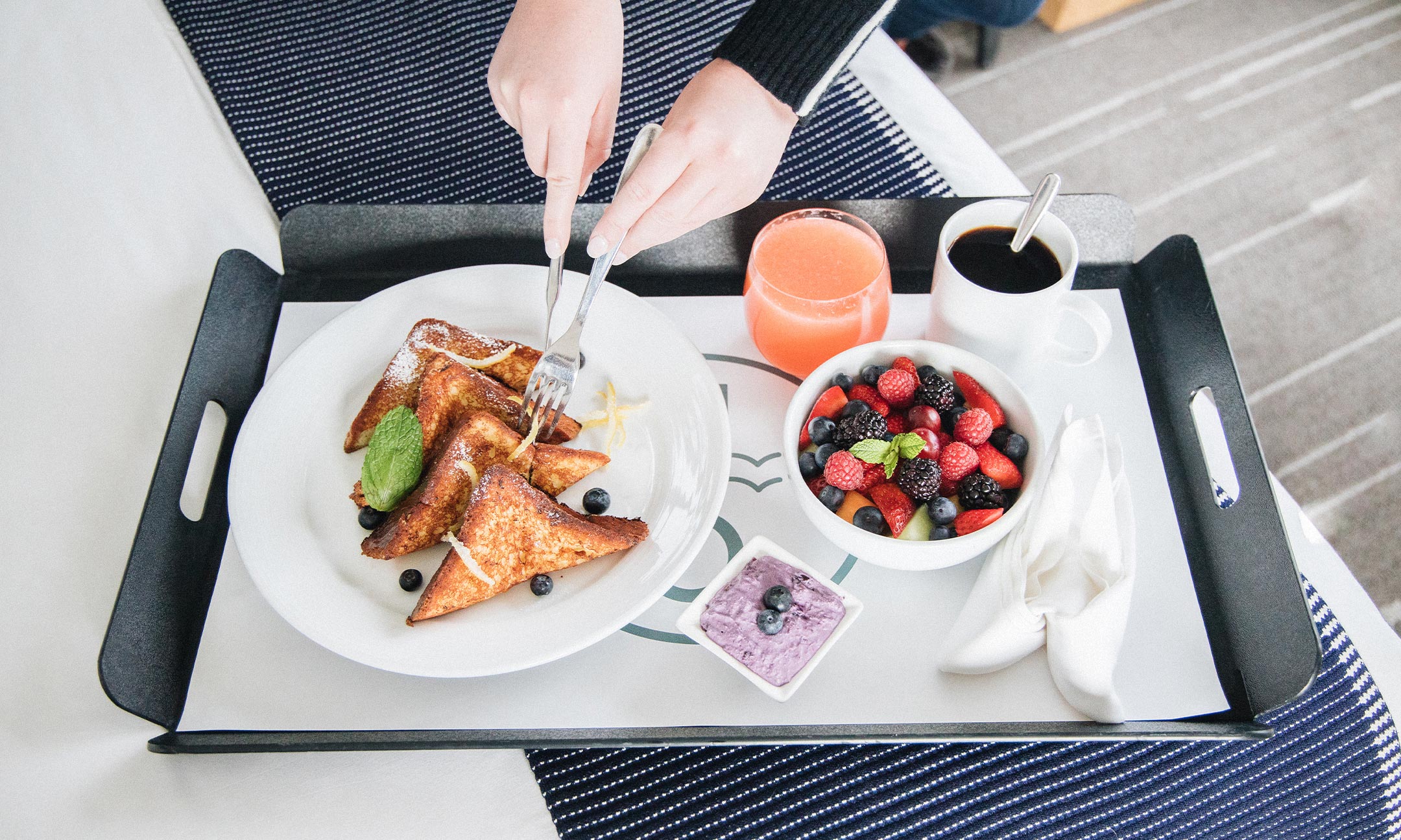 Overhead shot of french toast with a bowl of fruit, juice, coffee, and yogurt