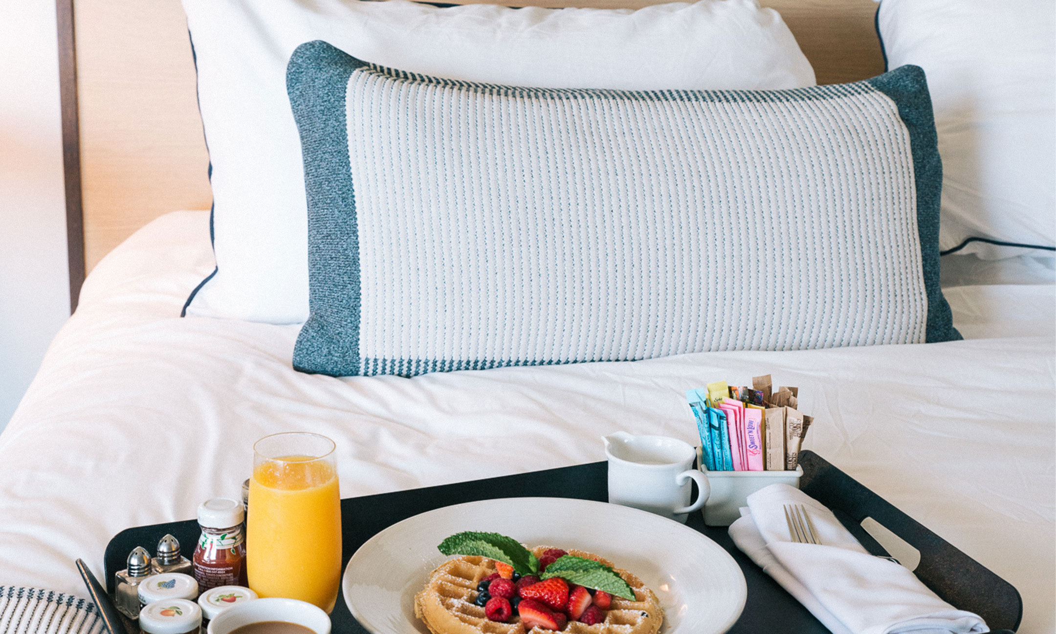 Breakfast tray with waffle, coffee, and orange juice on bed
