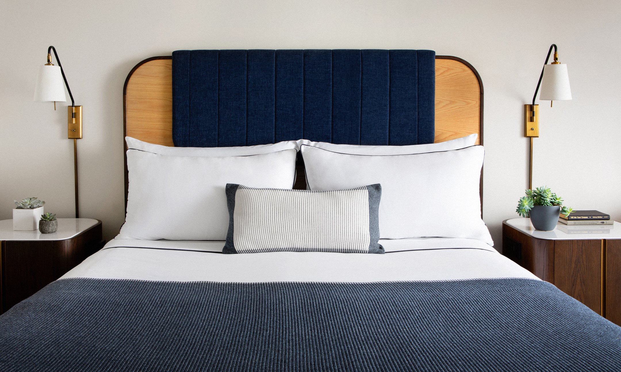 bed with wall sconces and nightstands on either side