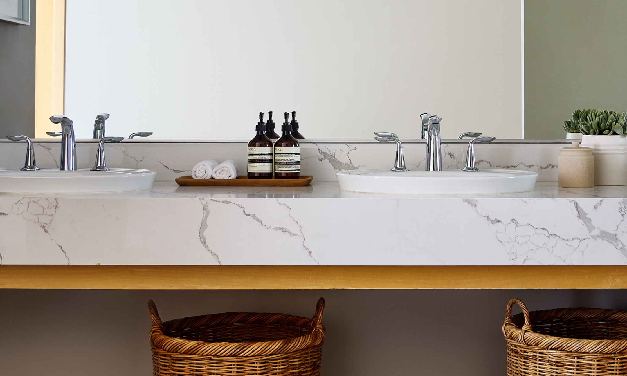 Marble top bathroom counter with two sinks, toiletries and vanity.