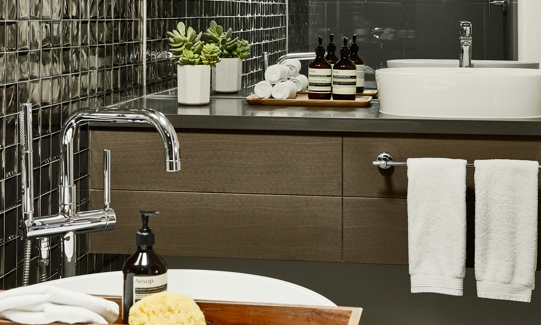 Bathroom with metallic tiles, soaking tub, walk-in shower and vanity.