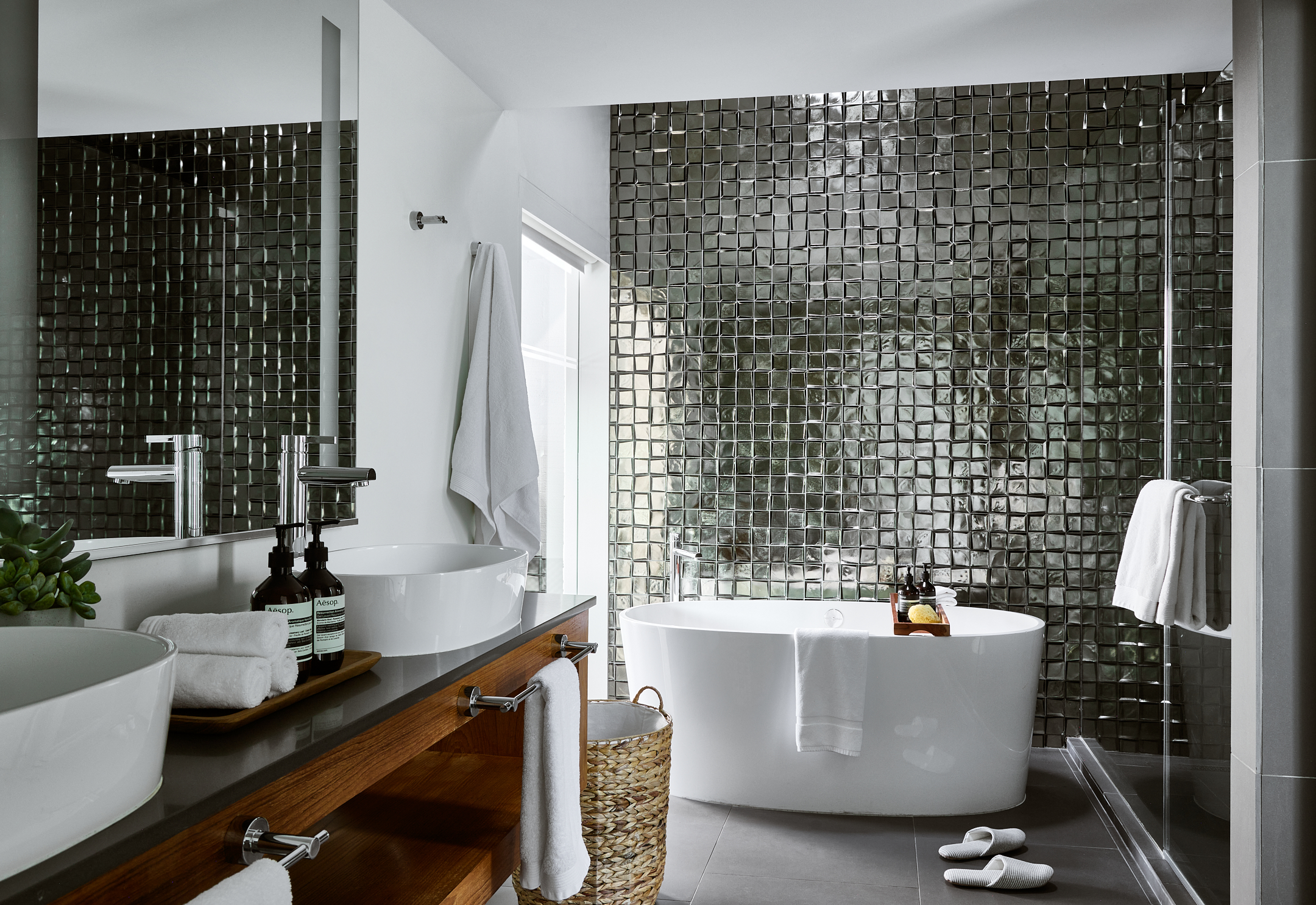 Metallic tiled bathroom with two sinks, vanity,  oversized soaking tub and walk-in shower.