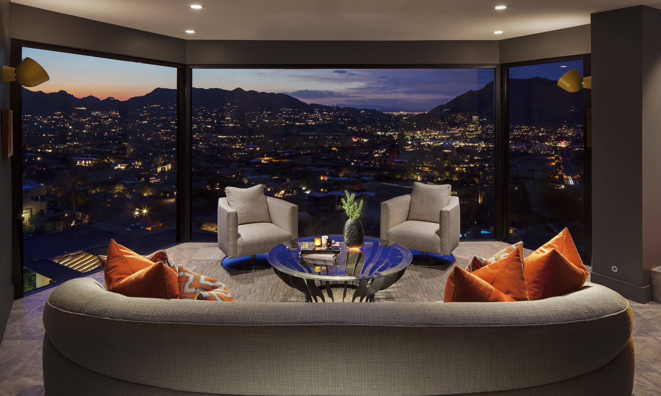 Seating area with floor-to-ceiling windows overlooking valley at night.