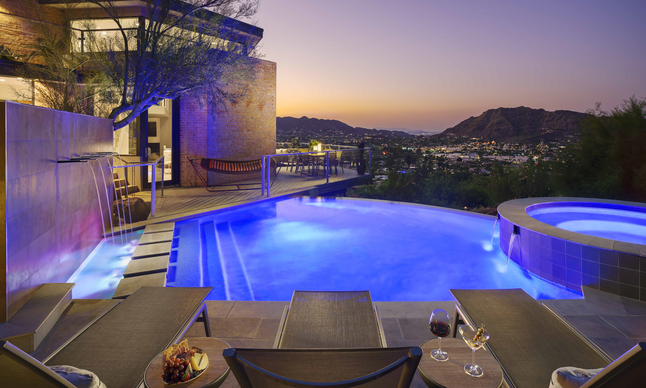 Three lounge chairs overlooking pool with water feature and hot tub with views of surrounding valley.