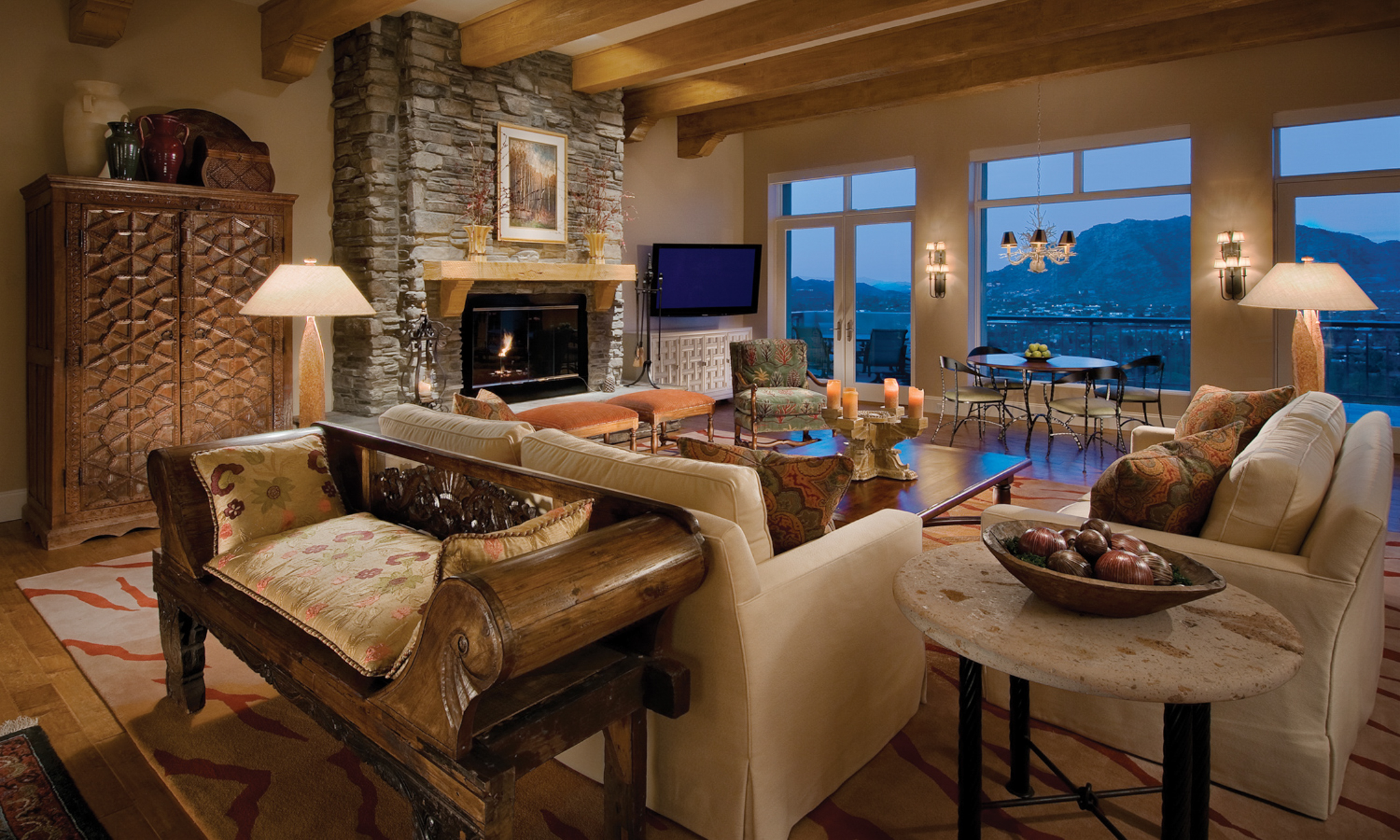 Living room sitting area with couch, chairs, fireplace and views of surrounding valley.