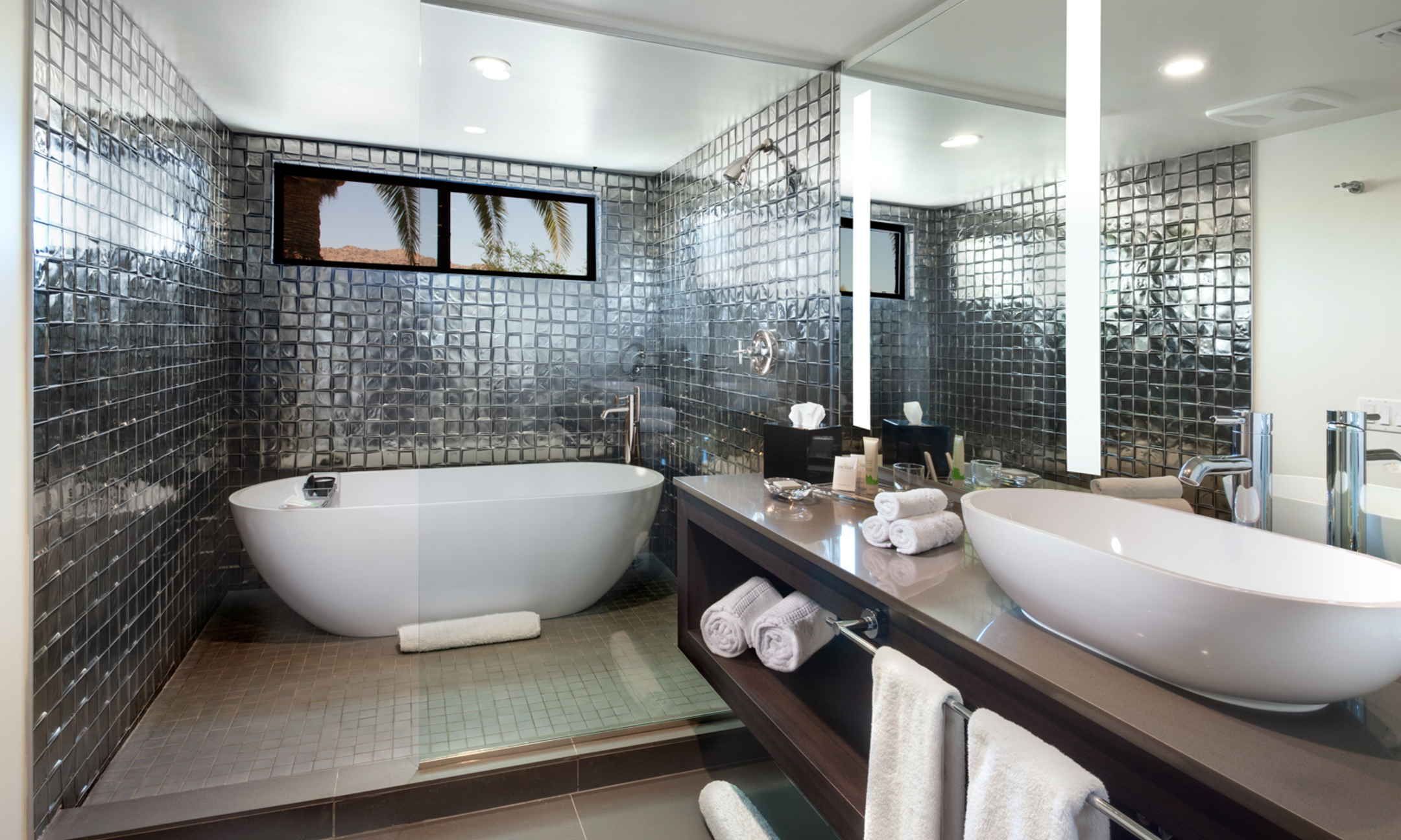 Metallic tiled bathroom with sink, soaking tub and walk-in shower.
