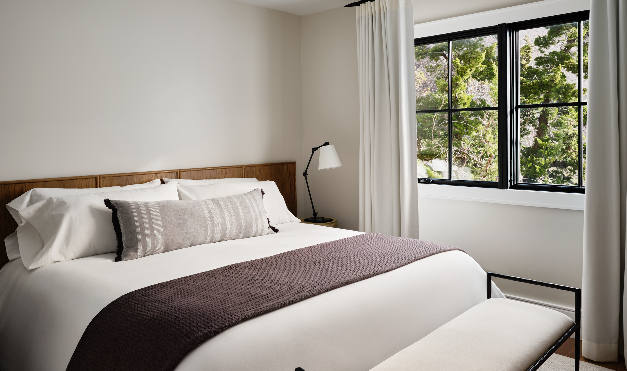 Bedroom with king bed, throw blanket, nightstand and window.