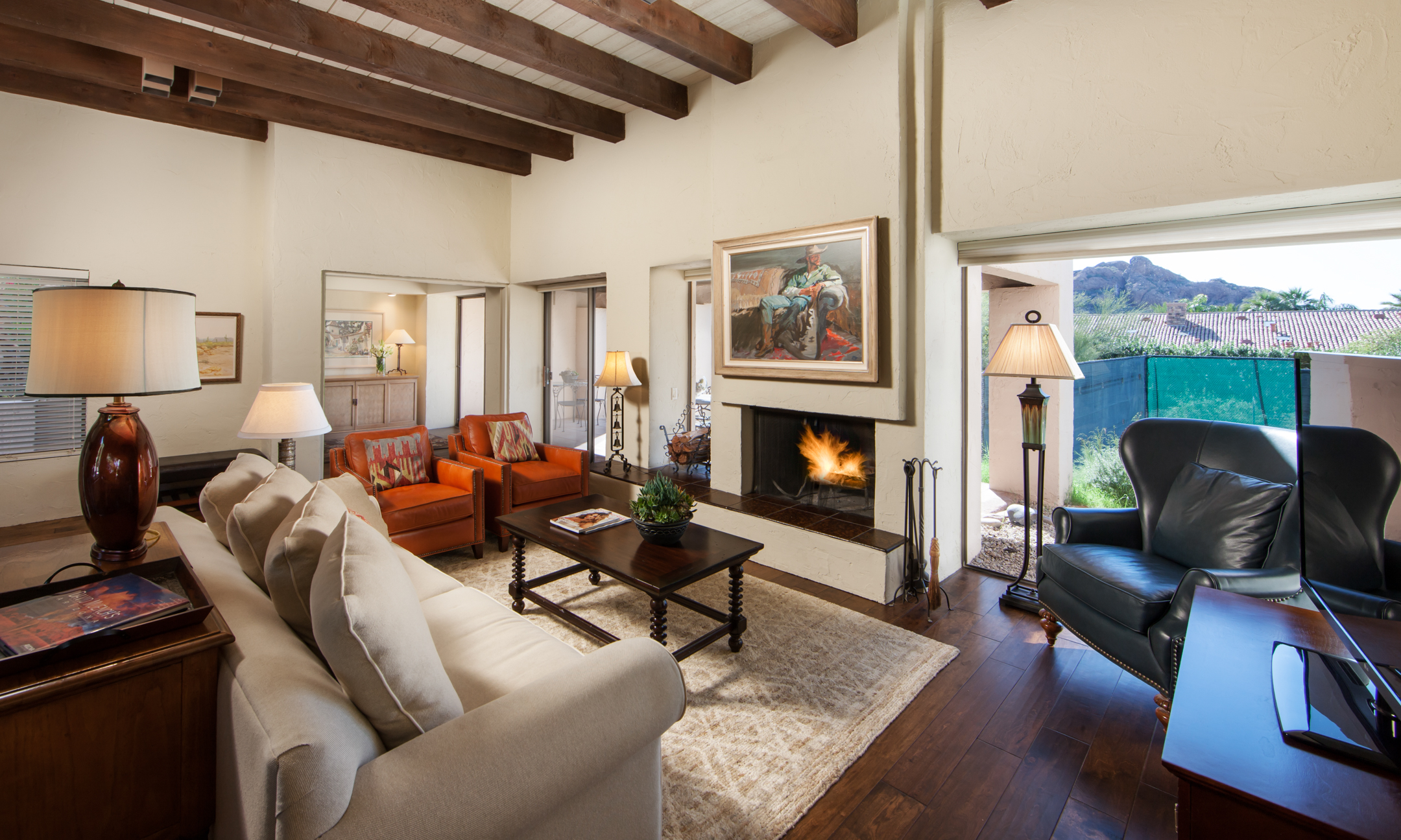 Villa Norte living room with couch, chairs, fireplace and view of Camelback Mountain.