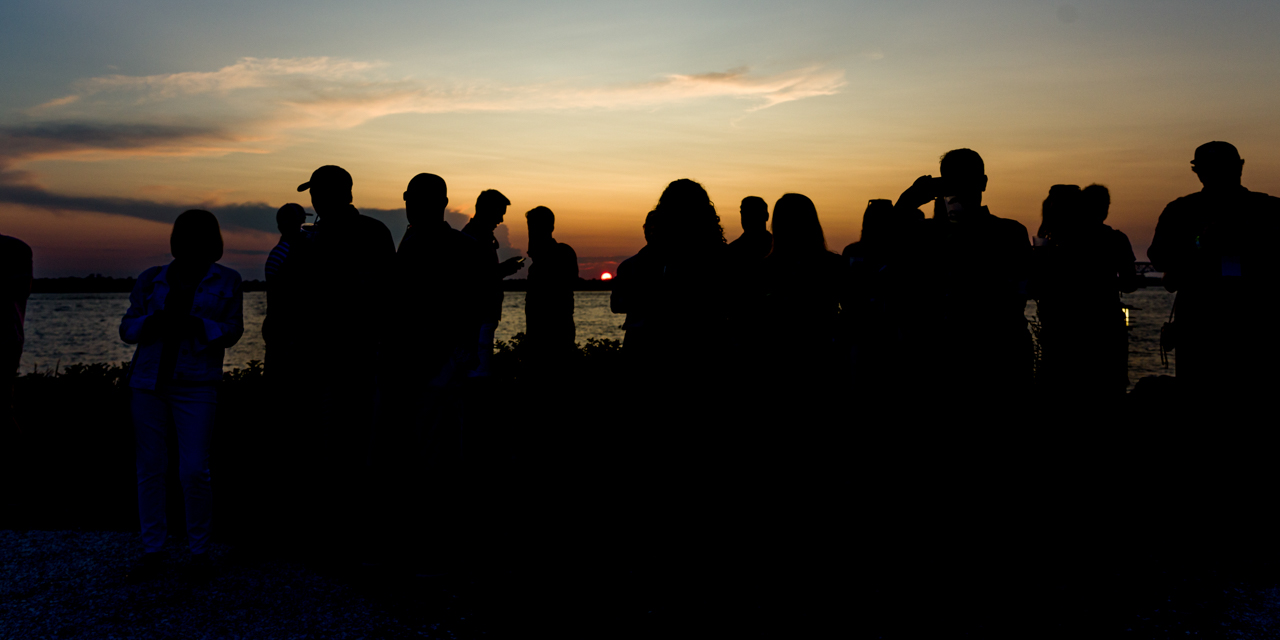 Crowd enjoying a live music and an ocean sunset.