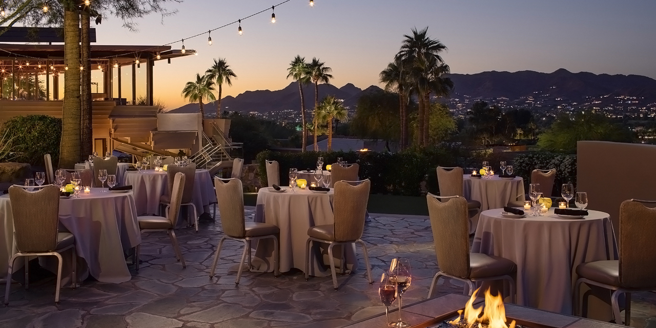 Paradise Views patio with tables and linens at dusk.