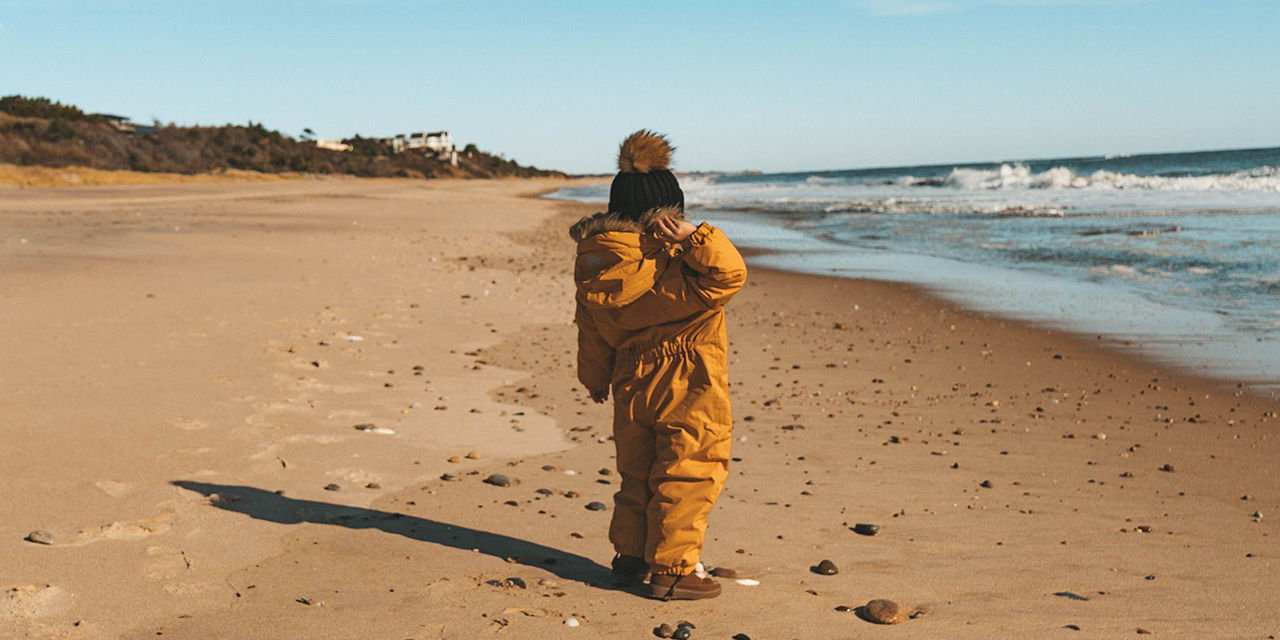 A child in winter clothes walks along the beach at Gurney's Montauk Resort