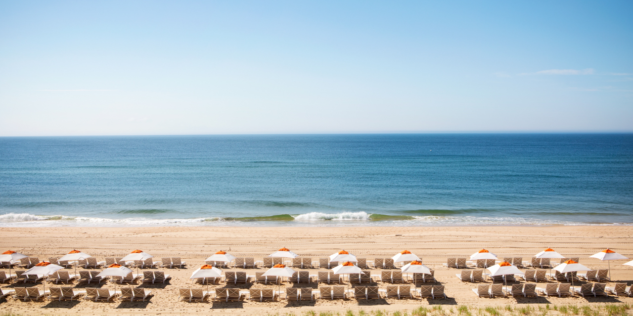 Daytime view of Montauk shoreline with chairs and umbrellas lining beach.