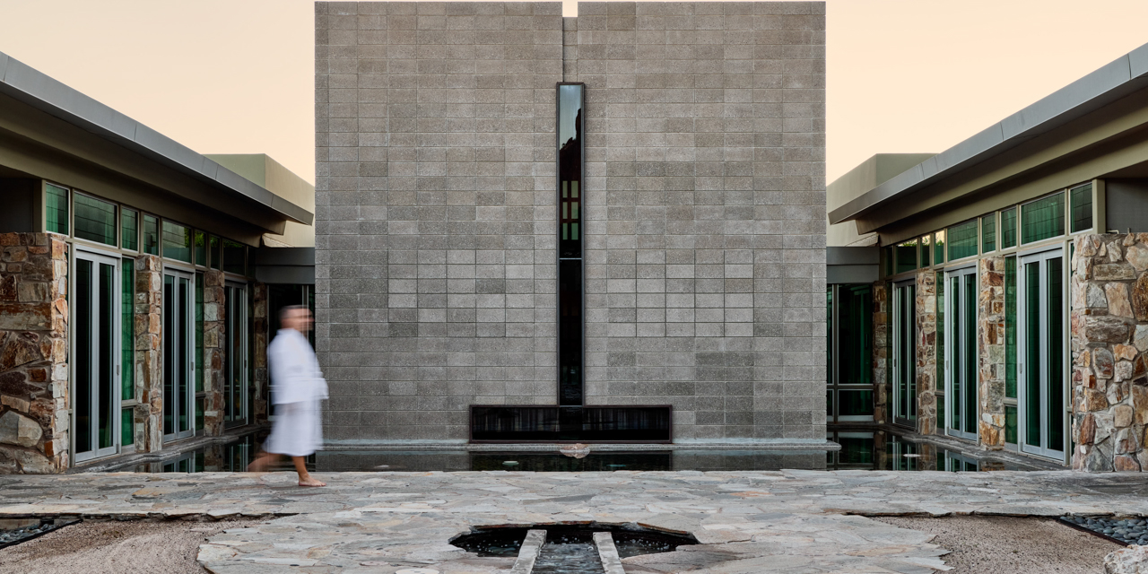 Man in robe walking through Sanctuary Spa Zen Courtyard.