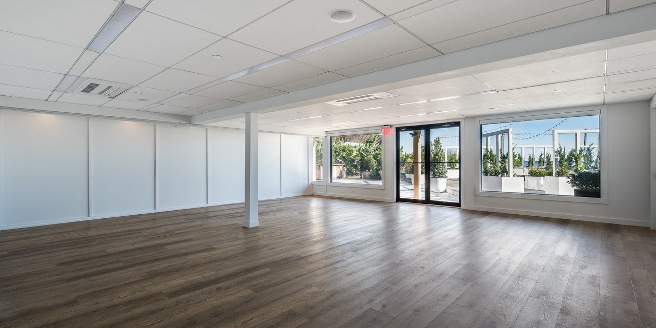 Latitude meeting venue with dark wood flooring, white walls and large windows with ocean view.