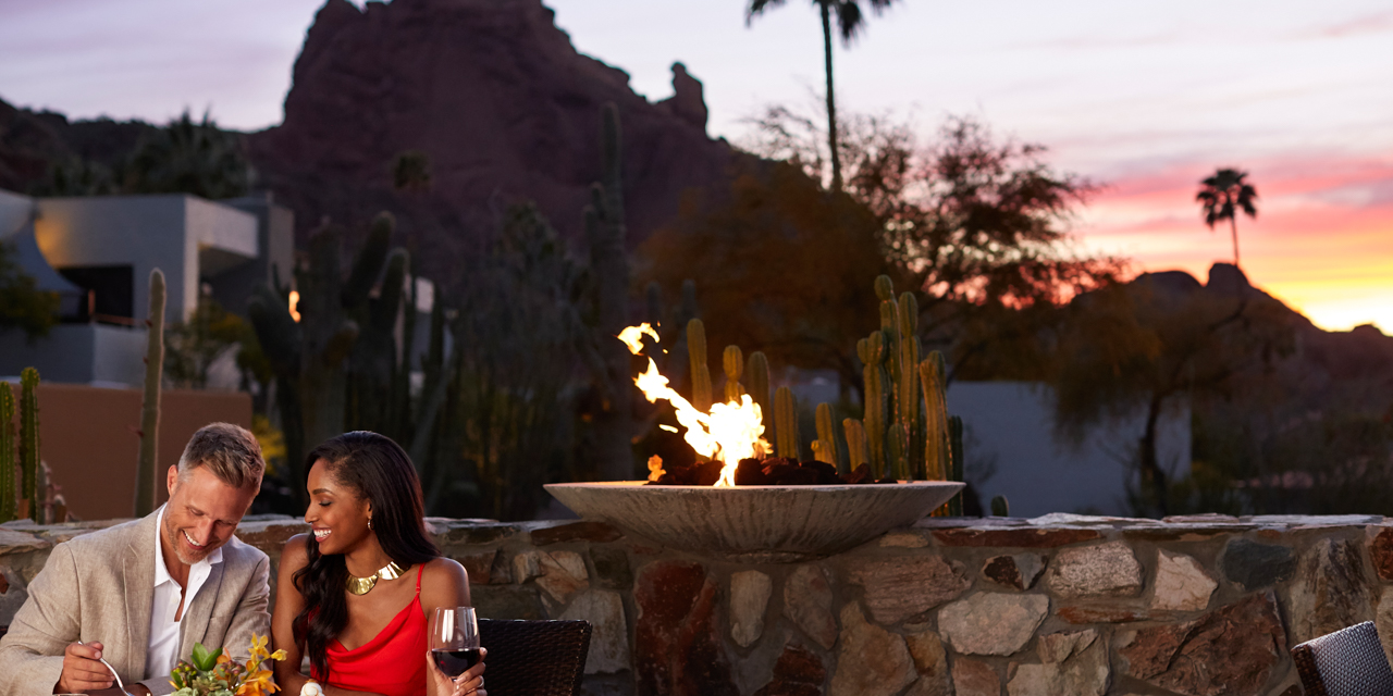 Couple enjoying a romantic meal at elements with sun setting over the mountain in background.