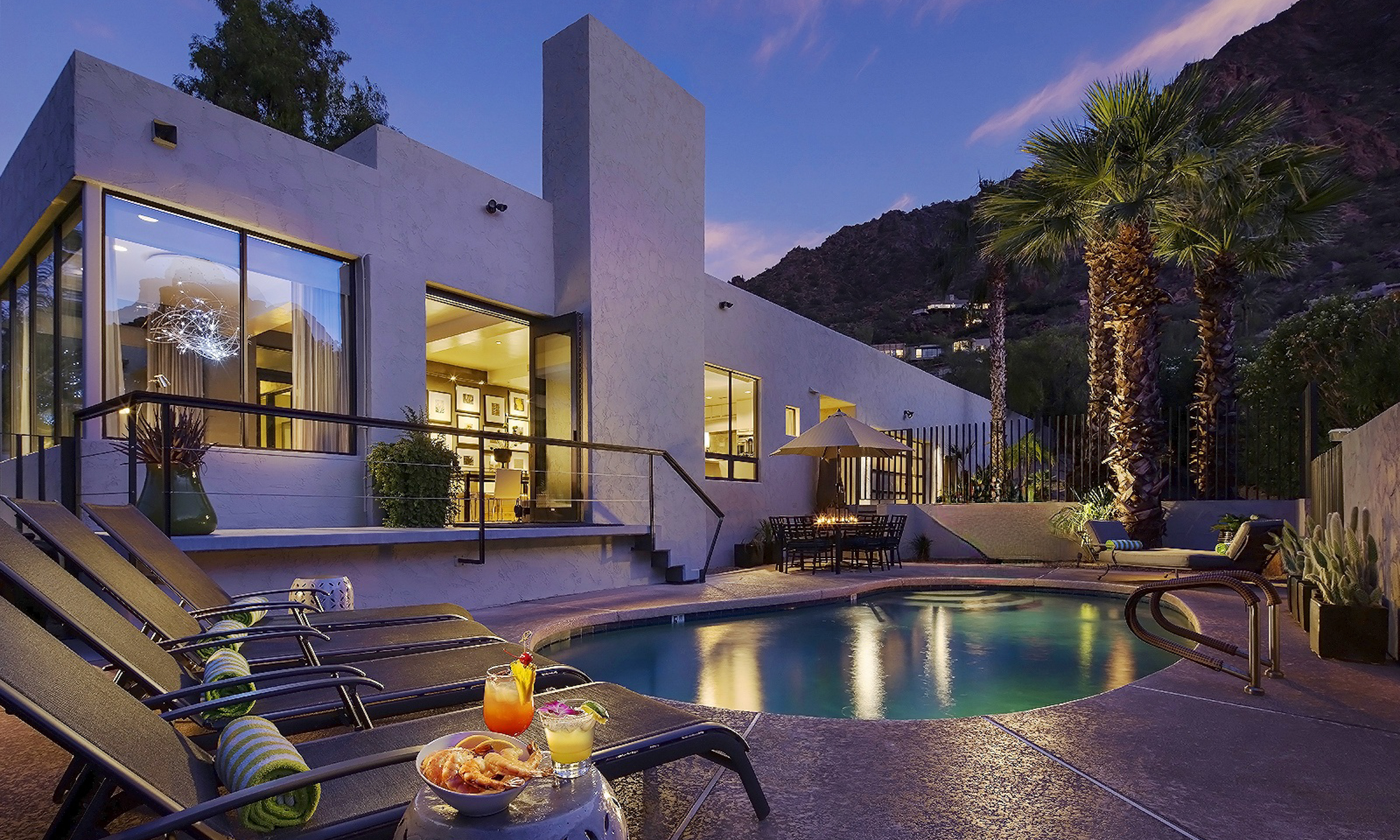 Outdoor pool with four lounge chairs and view of mountain.