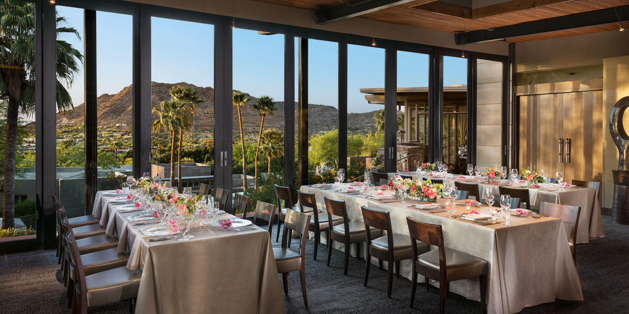 Tables set with white linen and spring florals with stunning valley views from floor to ceiling windows.