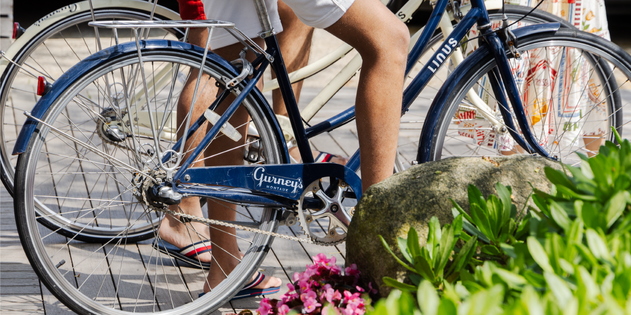 A man in shorts sits atop a blue beach cruiser at Gurney's Montauk resort