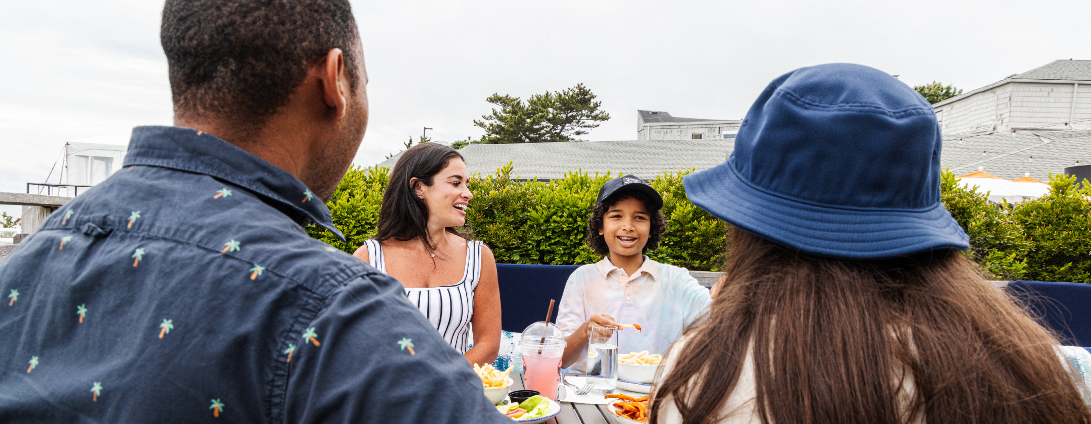 A group of people sitting at a table with food outdoors.