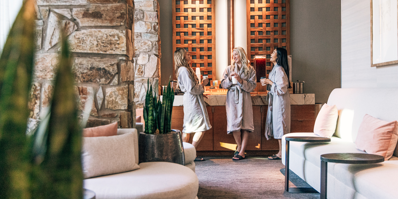Three woman in spa robes enjoying tea in women's locker room before spa treatments.