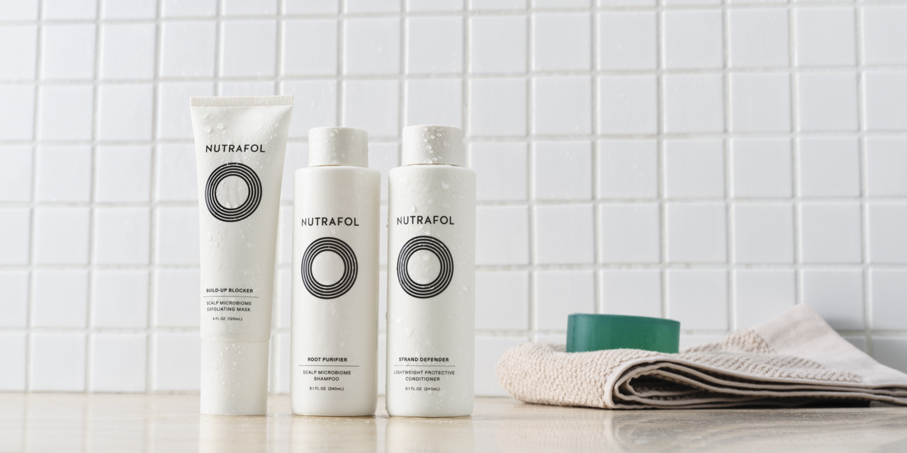 Three Nutrafol shampoo and scalp products displayed against white tile background.