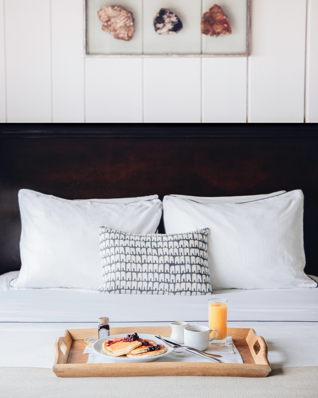 A tray of blueberry pancakes sits atop a crisp white bed