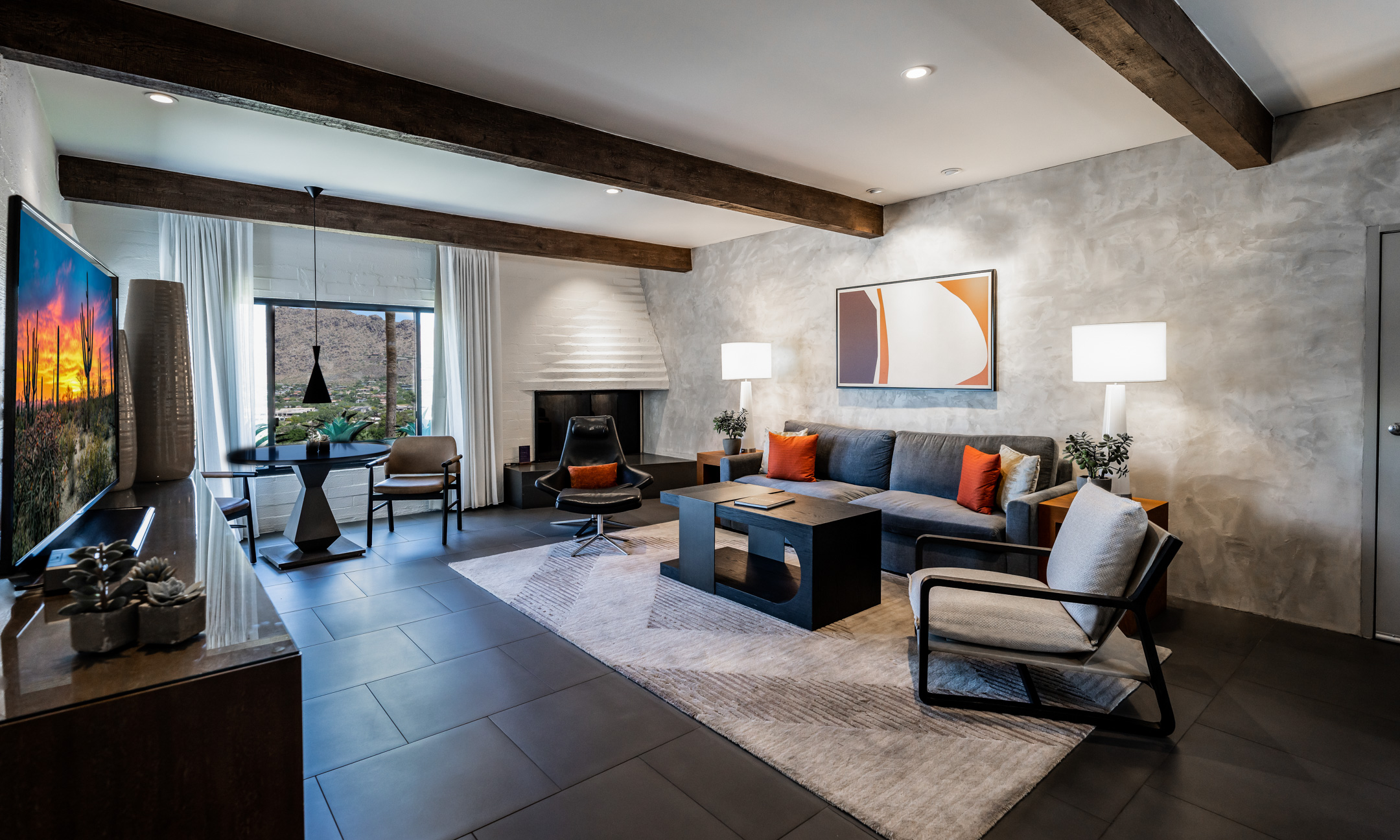 Accessible Mountain Suite living room with rug, accent wall, chair and couch, coffee table, fireplace and table and chairs overlooking view.