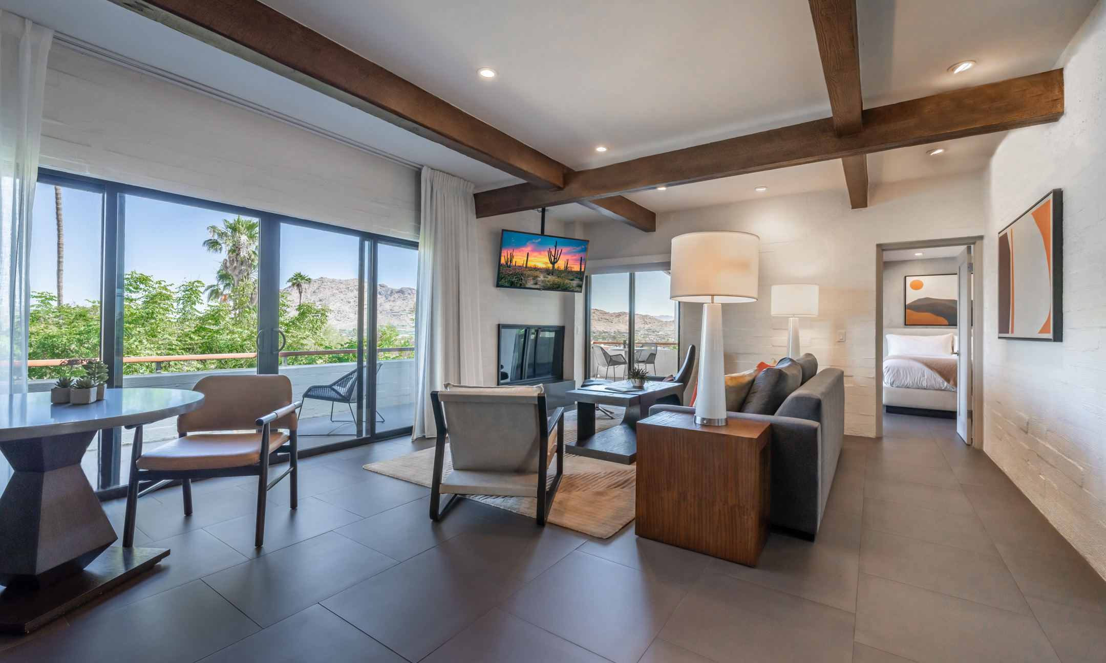 Camelback Suite living room seating area including couch and chairs, coffee table, fireplace and flatscreen television, table and chairs and wrap around patio.