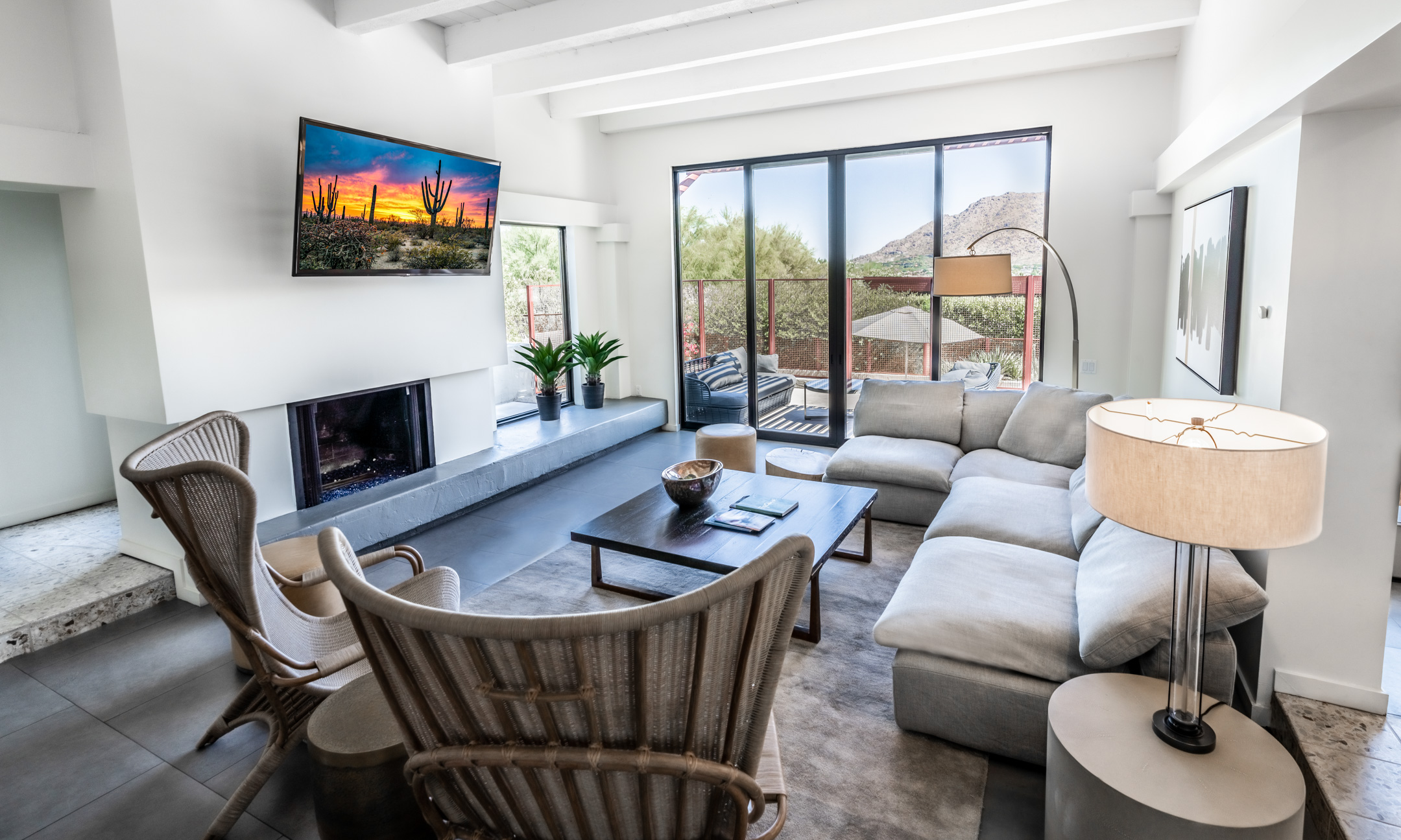 Living room with two wicker chairs, comfortable couch, fireplace and flatscreen television and outdoor patio and private pool access.