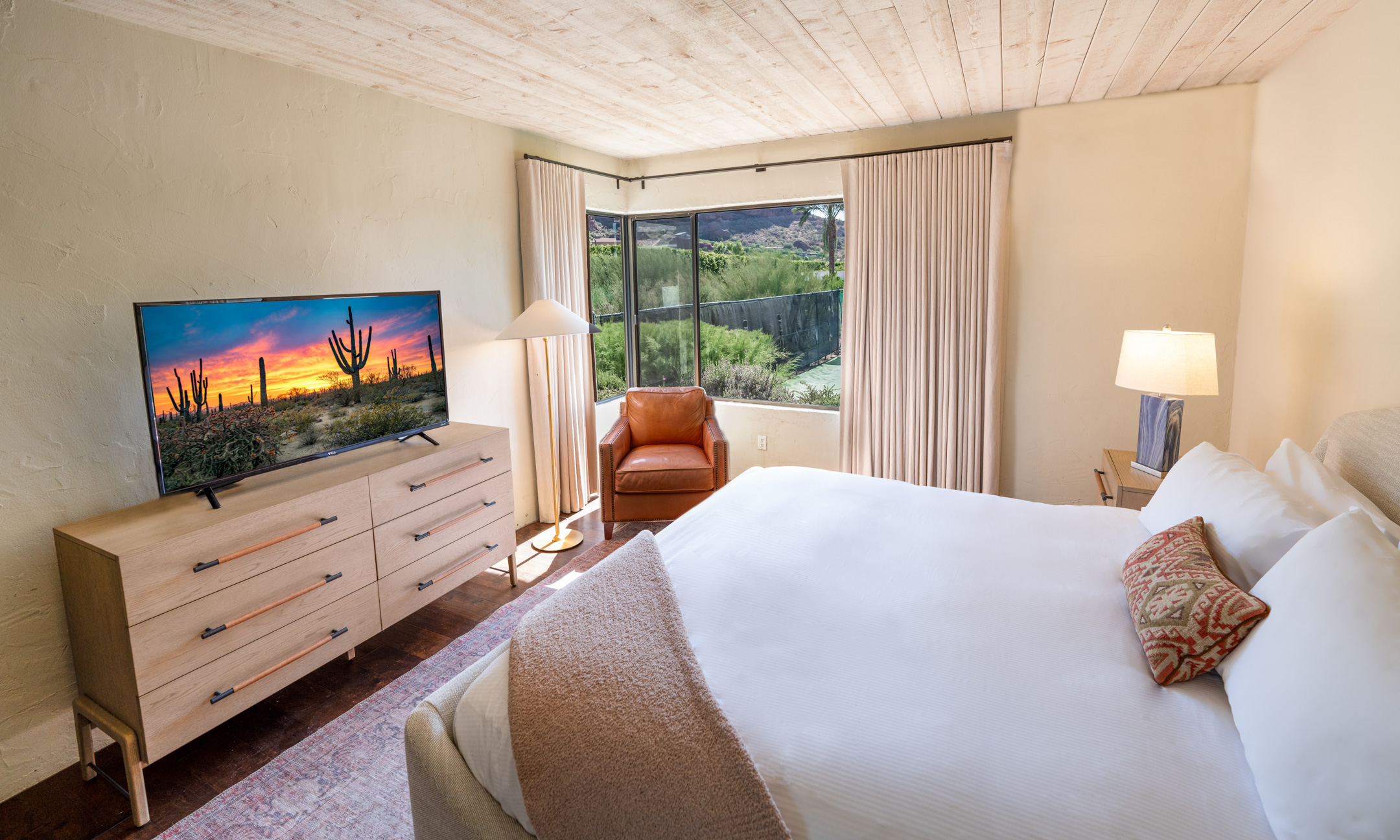 Bedroom with King bed, wood dresser and flatscreen, and comfortable leather chair.