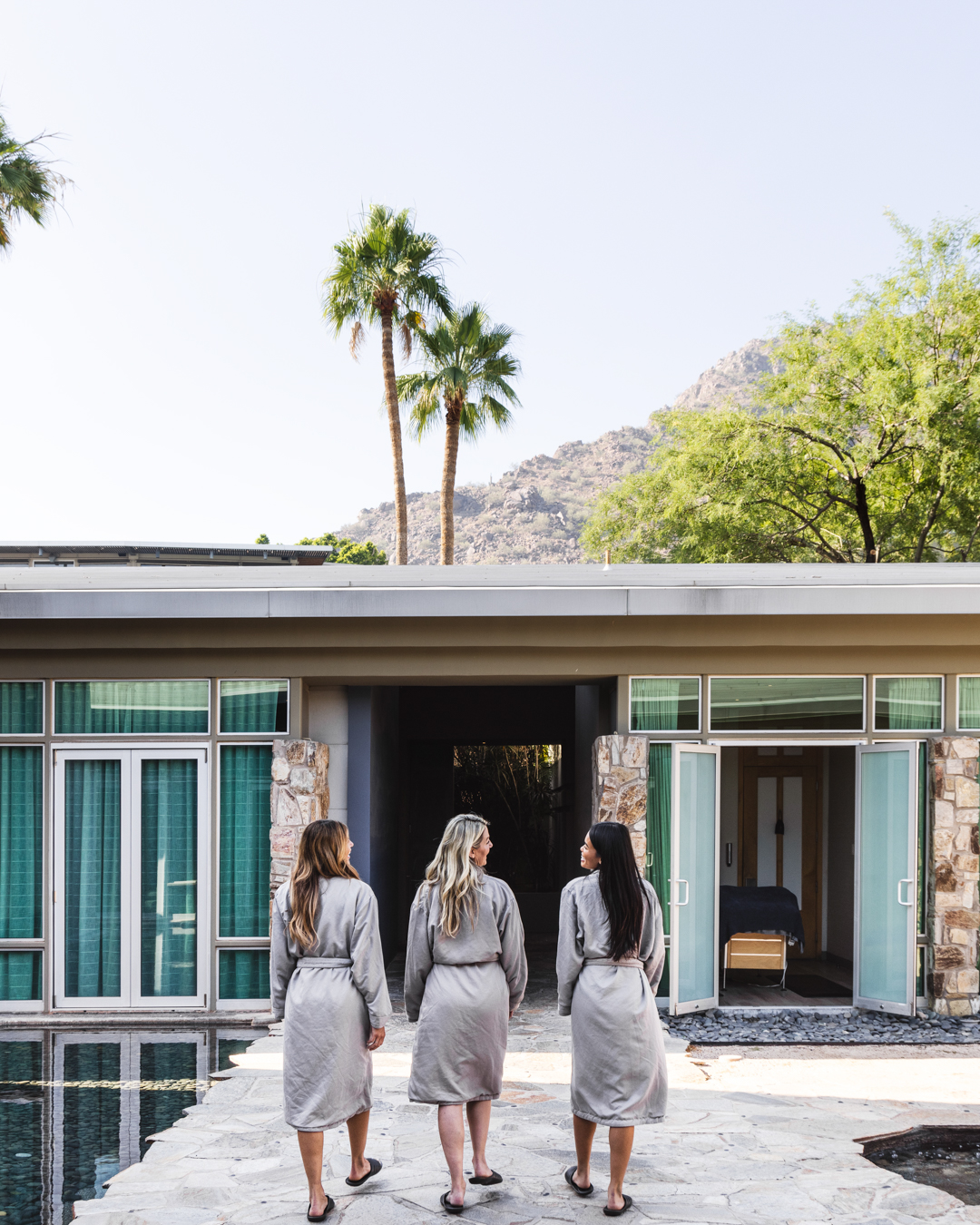 Three woman in spa robes walking through Sanctuary Spa's Zen Garden courtyard before treatments.