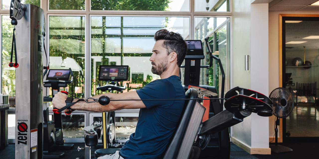 Man in fitness attire doing cable presses on cable machine in Sanctuary's fitness center.