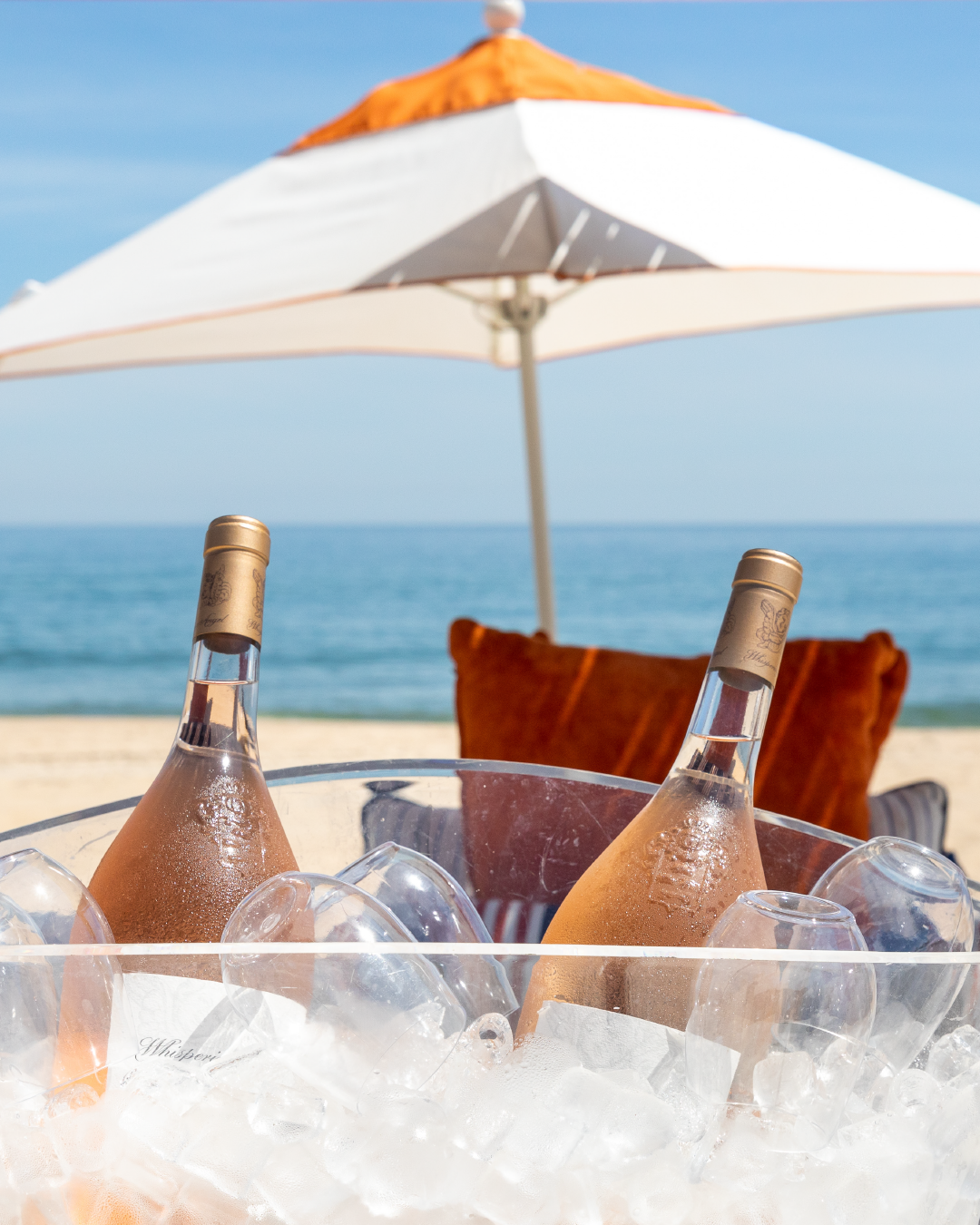Two bottles of wine set against an umbrella and an ocean backdrop