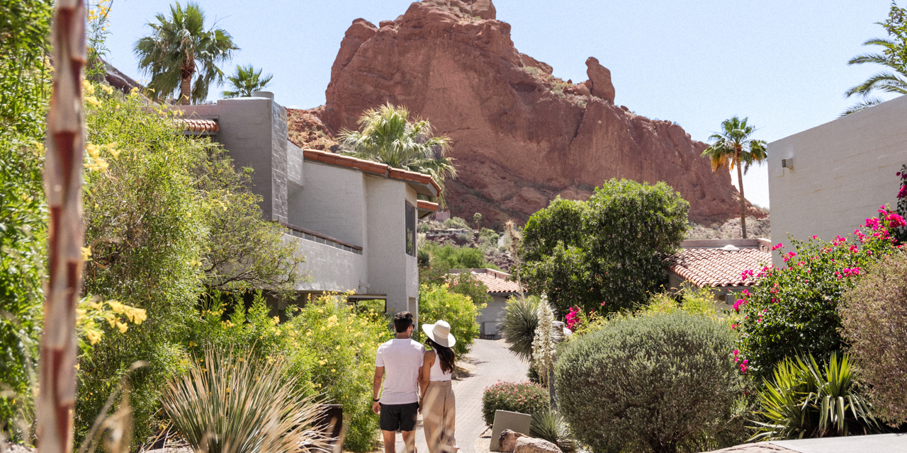 Couple in comfortable attire walking through lush, desert landscape outside Mountain Casitas and Suites.