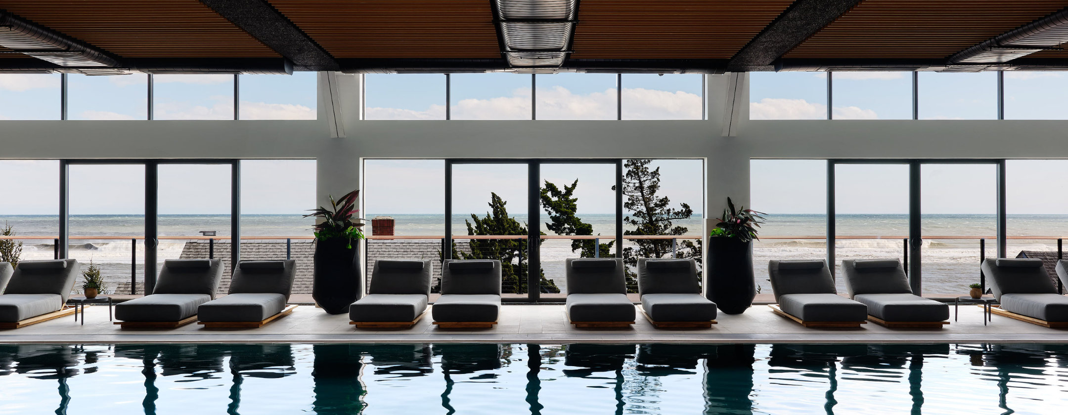 a large indoor pool with lounge chairs and a view of the ocean