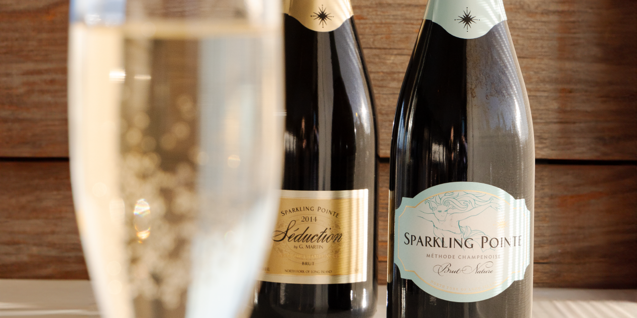 A glass of sparkling wine in the foreground and two bottles of Sparkling Pointe wine in the background
