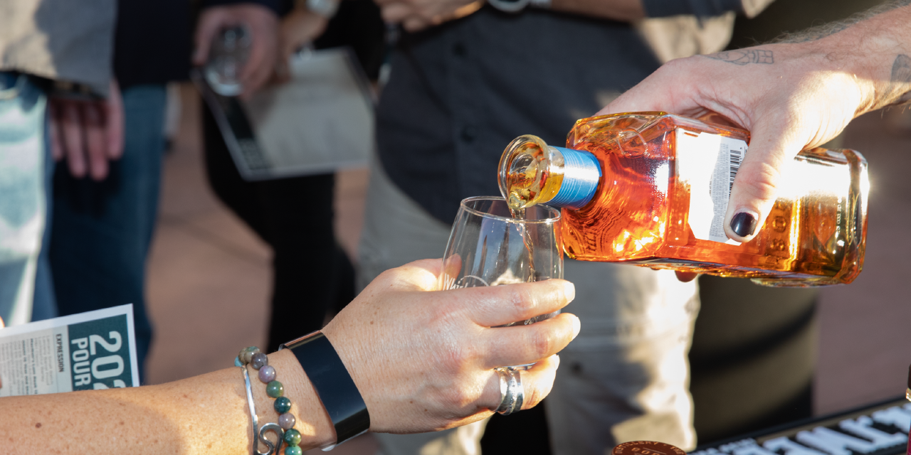 A closeup of a whisky pour into a small sample glass