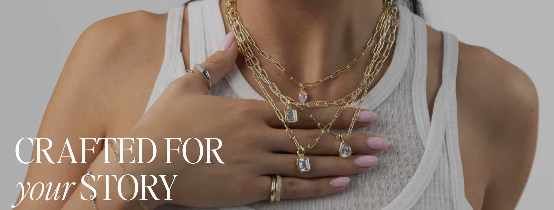 Woman wearing layered necklaces, rings, and a white tank top. Text on the left reads "CRAFTED FOR your STORY."